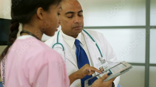 Doctor is given information by his nurse who is using an electronic tablet pc.