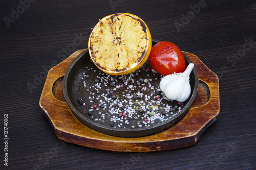 Grilled lemon, tomato and garlic with herbs in a cast iron fryin photo