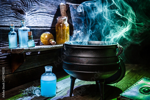 Vintage witcher cauldron with blue smoke and potions for Halloween photo