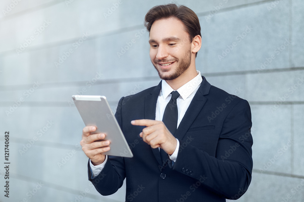 Successful businessman working on tablet while standing outdoors
