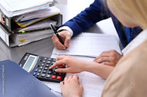 Bookkeeper or financial inspector and secretary making report, calculating or checking balance. Internal Revenue Service inspector checking financial document. Audit concept.