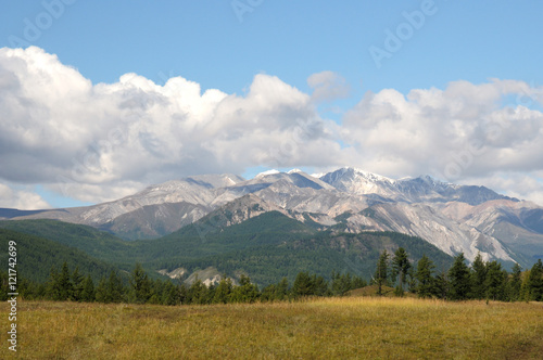Blue sky and cumulus clouds over the Eastern Sayan Mountains and Mount MunKu-Sardyk. Photo partially tinted. © Евгений Кожевников