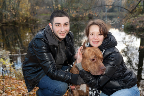 Couple in love, and American Pit Bull Terrier in the autumn park © annatronova