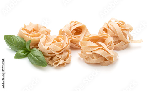 Italian pasta fettuccine nest and basil leaves isolated on whit