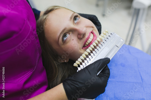 Close up portrait of Young women in dentist chair, Check and select the color of the teeth. Dentist makes the process of treatment in dental clinic office.Dentist