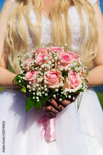 Bride with pink roses bouquet in her hands. Closeup
