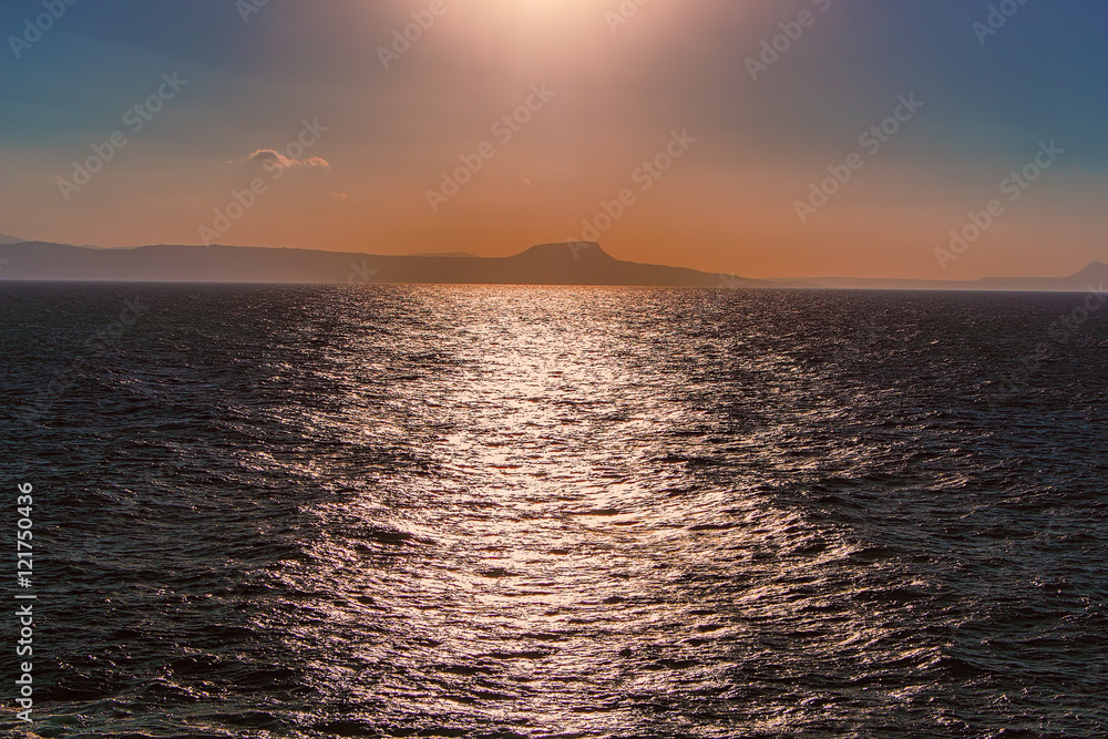 Obraz premium Dark blue sea with island on horizon in the evening, sunset.