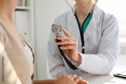Doctor with a stethoscope in the hand. Physician examines her female patient.