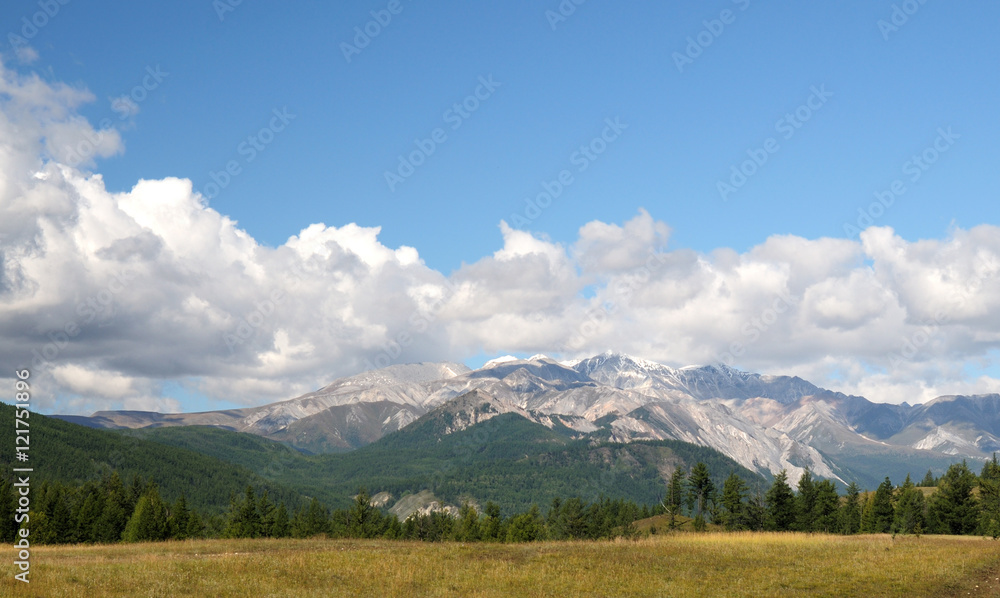 Blue sky and cumulus clouds over the Eastern Sayan Mountains and Mount MunKu-Sardyk. Photo partially tinted.