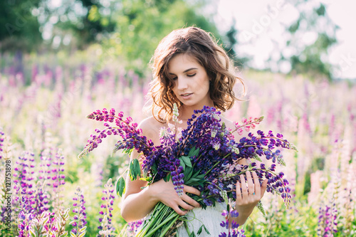 Girl with a bouquet of lupine on the field