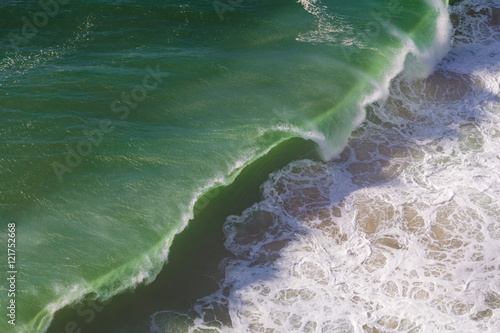Top view of isolated emerald ocean waves with white foam, Praia do Norte, Nazare, Portugal