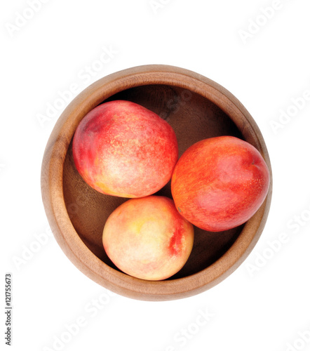 Nectarines in wooden bowl on a white background