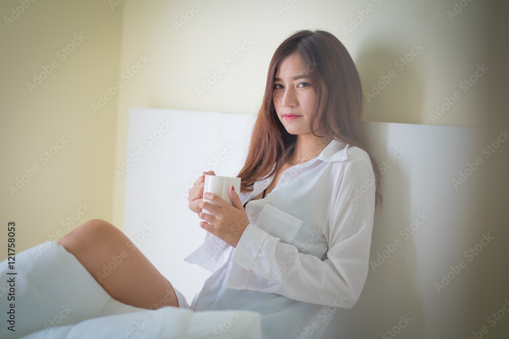 Beautiful brunette woman drinking and morning coffee in bedroom Beautiful brunette woman drinking and morning coffee in bedroom