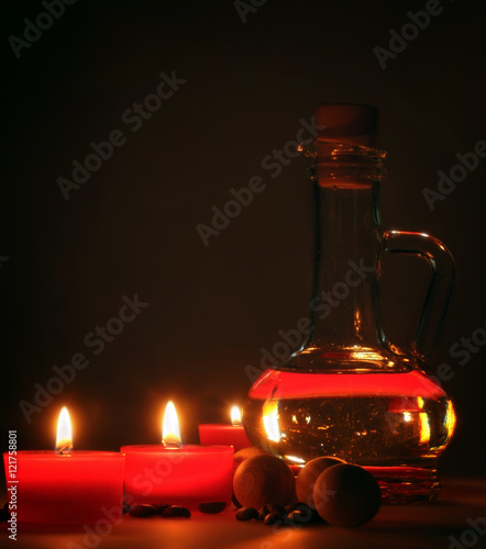 spa composition. scented candles, coffee beans, aromatic wooden balls and oil in a glass jug with a stopper.  partially tinted photo. photo