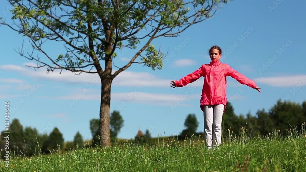 Girl in red sports jacket make physical exercises on the nature. Physical activity helps burn up calories. Girl goes in for sports. Girl engaged in fitness. Morning physical exercises Girl in red sports jacket make physical exercises on the nature. Physical activity helps burn up calories. Girl goes in for sports. Girl engaged in fitness. Morning physical exercises