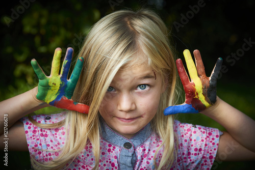 cute girl showing her colorful hands. Girl have fun painting her hands outside in the garden.