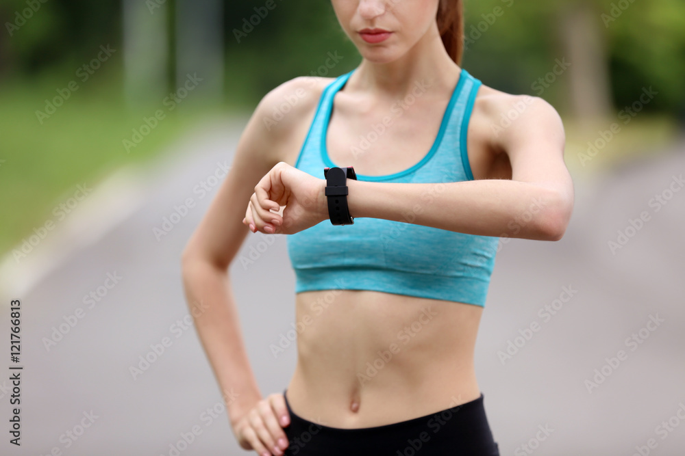 Young woman checking time after run in park Young woman checking time after run in park