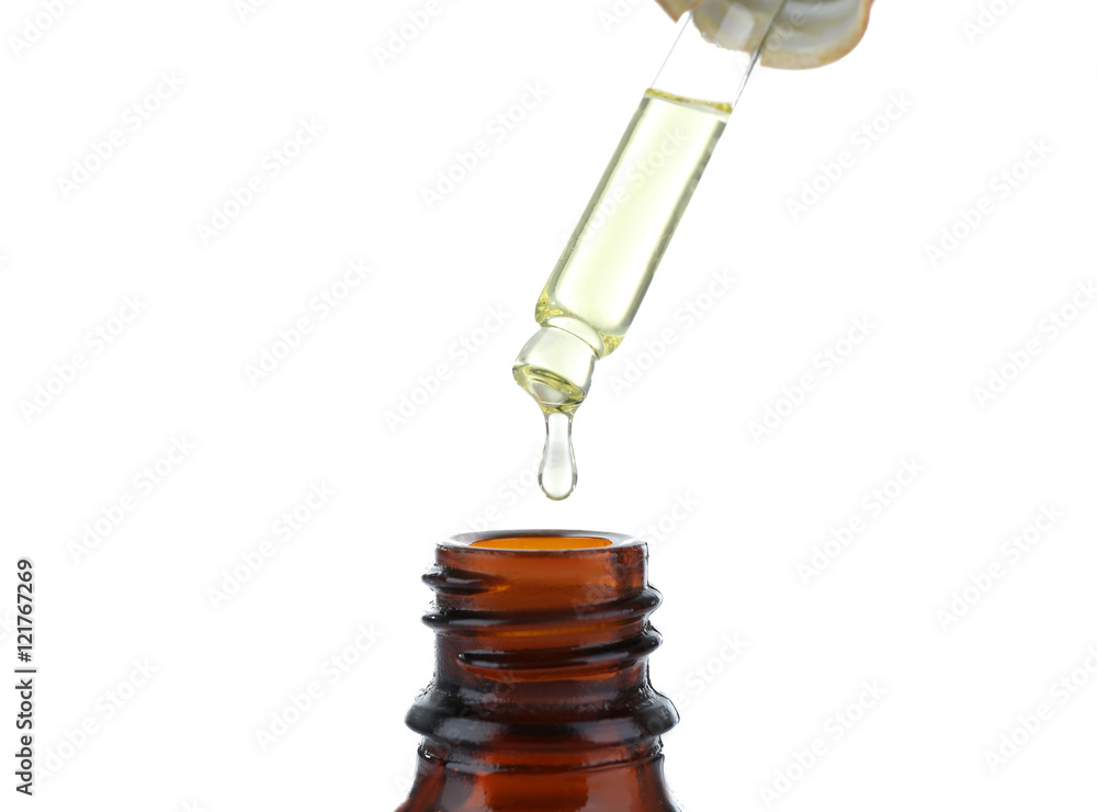 Mint oil dripping from pipette into glass bottle on white background Mint oil dripping from pipette into glass bottle on white background