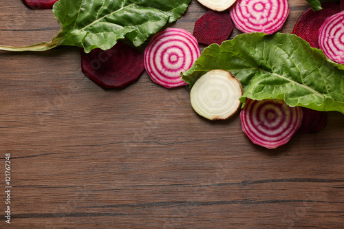 Fresh sliced beetroots with tops on wooden background