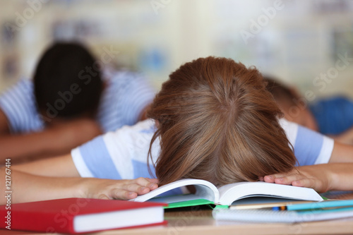 Tired schoolgirl in classroom on lesson