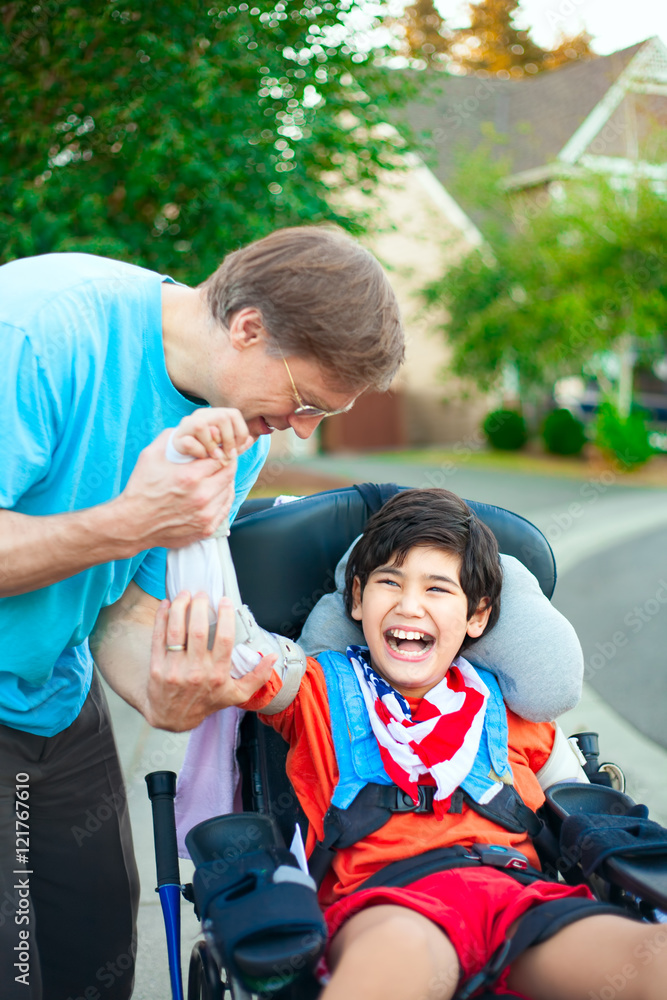 Fotografie Father helping disabled son adjust arm guards orthotics