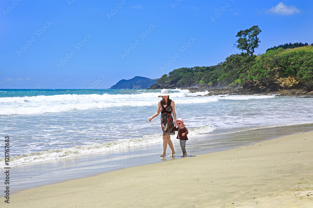 Young pretty woman with her daughter strolling along Sandy Beach Young pretty woman with her daughter strolling along Sandy Beach