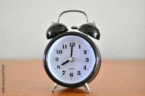 The black alarm clock is showing time at eight o'clock