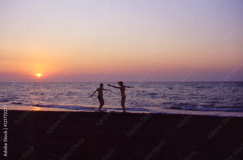 ragazzo e ragazza che giocano sulla spiaggia al tramonto
