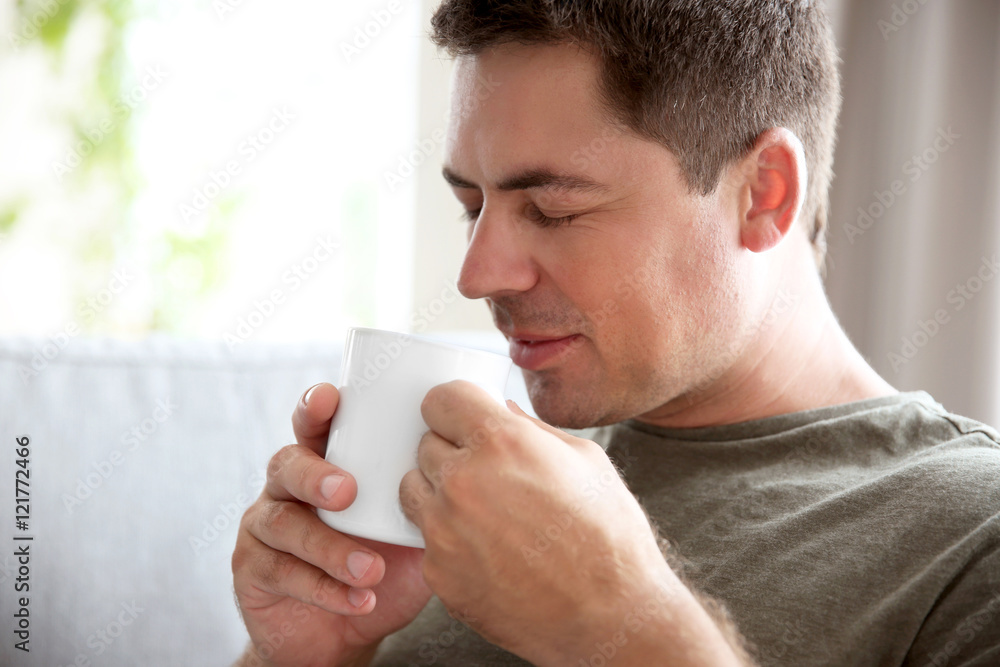 Handsome man sitting on couch with cup of coffee Handsome man sitting on couch with cup of coffee