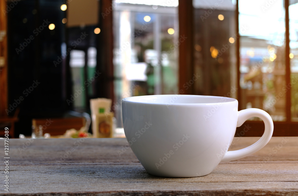 White Coffee cup on wooden table in coffee shop blur background.