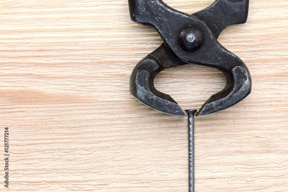 old black rusty nippers and nail on wooden background old black rusty nippers and nail on wooden background