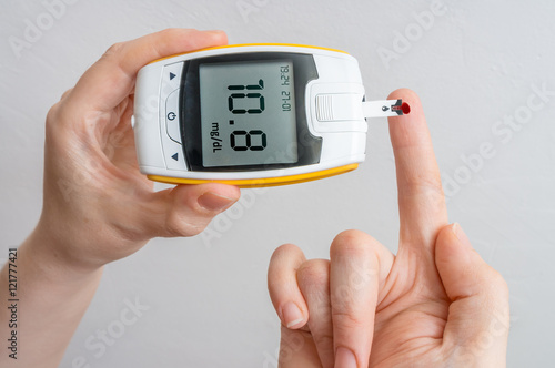 Diabetic patient is holding glocimeter and measuring glucose level in blood.