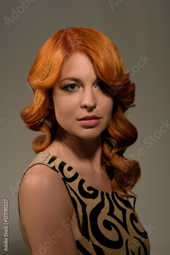Portrait of beautiful young red haired woman with fashion makeup and hairstyle posing in the studio