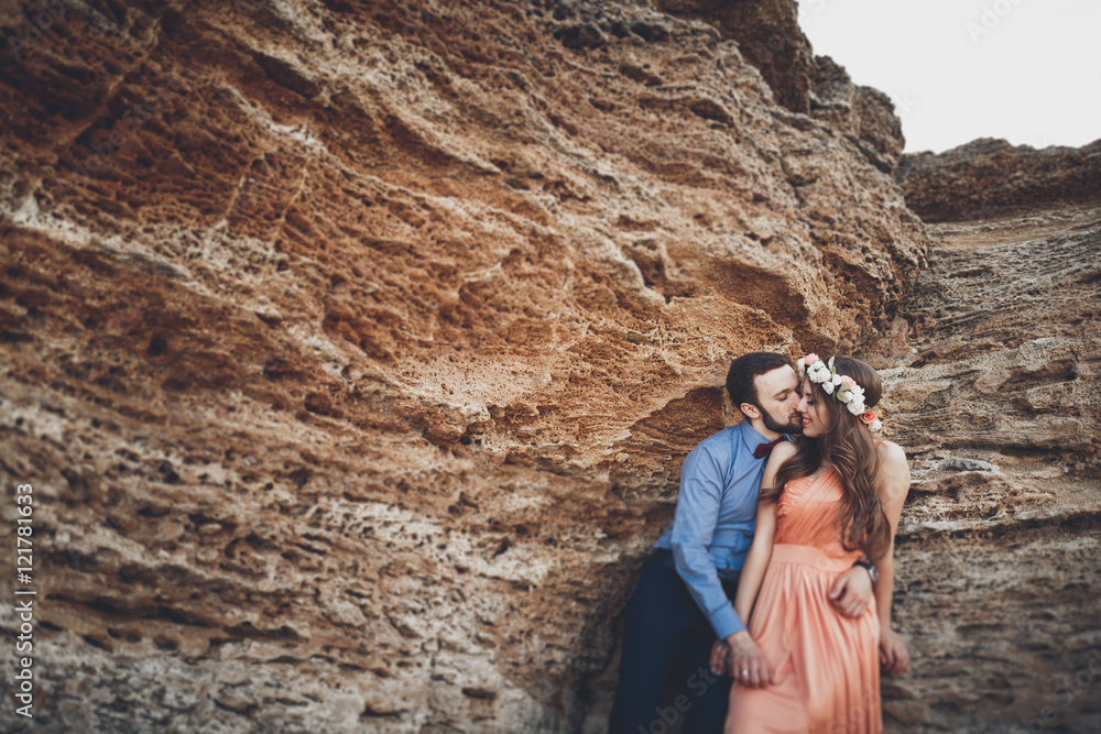 Fototapeta premium Romantic loving couple walking on the beach with rocks and stones