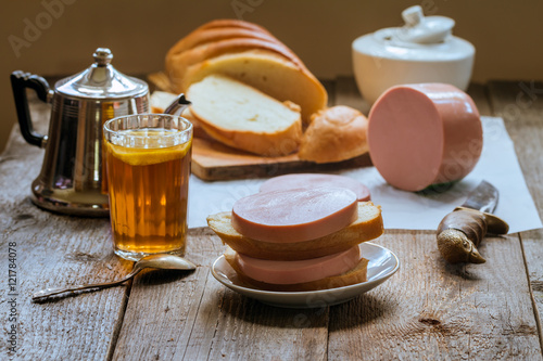 sandwich with boiled sausage and tea glass
