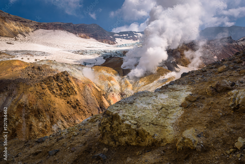 River flowing through the canyon with fumaroles inside Mutnovsky Volcano crater, Kamchatka, Russia