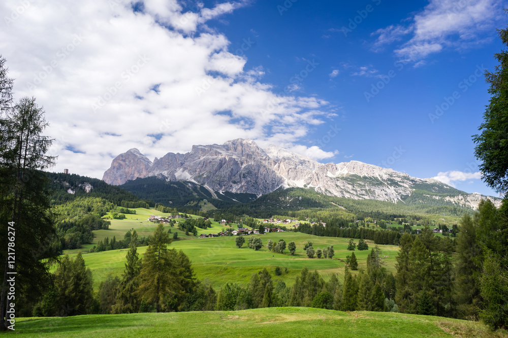 Typical summer scene in Italian Dolomites. Traditional mountain houses with majestic mountains in background.