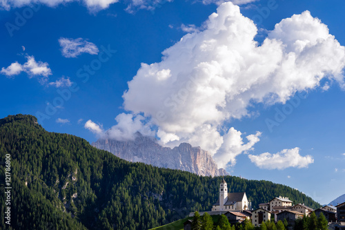 Typical summer scene in Italian Dolomites. Traditional mountain church with majestic mountains in background.
