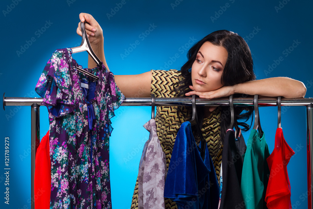 Sad Woman Under The Clothing Rack With Dresses  