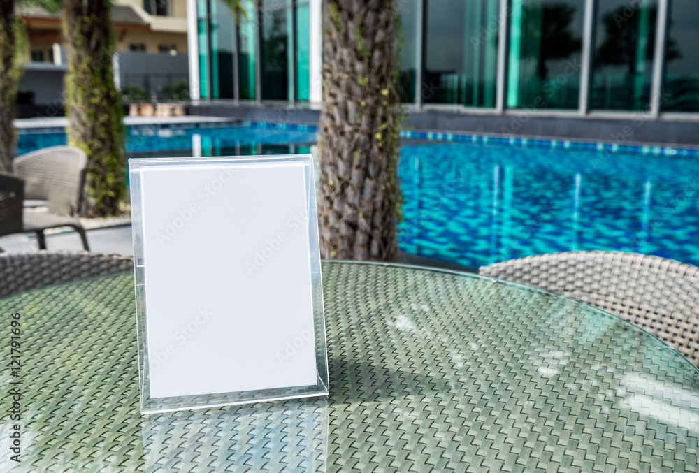 Naklejka premium Signboard blank on glass table at side swimming pool