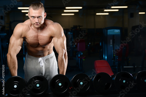 Handsome muscular bodybuilder man doing exercises in gym.