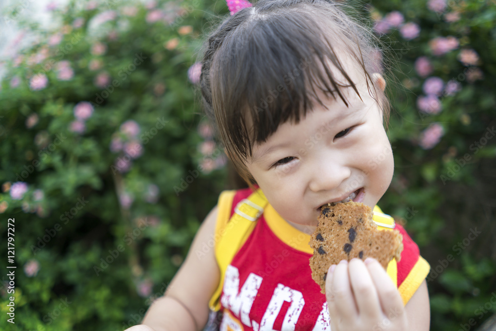 Close up asian little girl eating a cookie Close up asian little girl eating a cookie