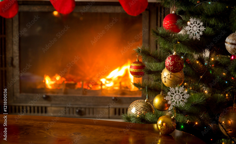 Decorated Christmas tree next to burning fireplace with natural