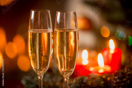 Closeup of two glasses of Champagne in front of burning candles