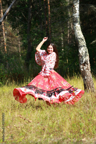 Gypsy girl in national dress dancing in the forest