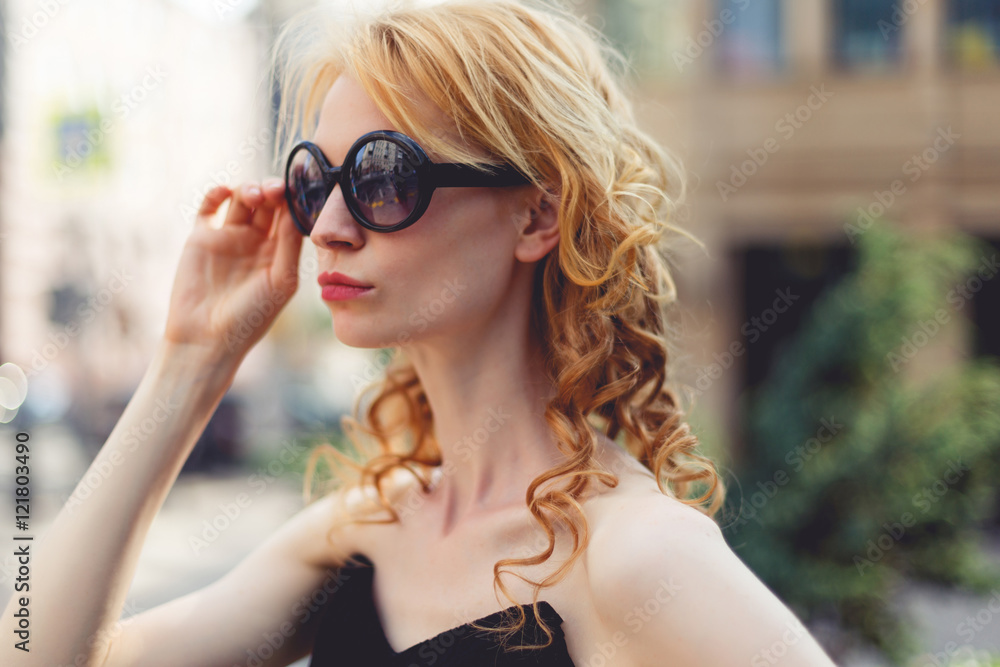 Ginger woman in sunglasses standing sideways , tinted photo Ginger woman in sunglasses standing sideways , tinted photo