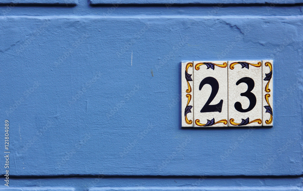 Ornate number 23 on a ceramic tile on a blue background