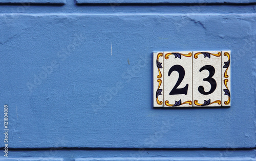 Ornate number 23 on a ceramic tile on a blue background © jahina_photos