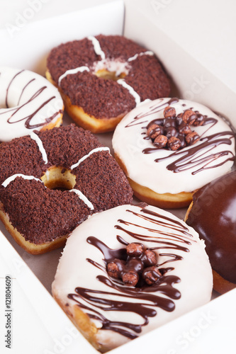 Chocolate sweet donuts with sprinkles in a box on a white background
