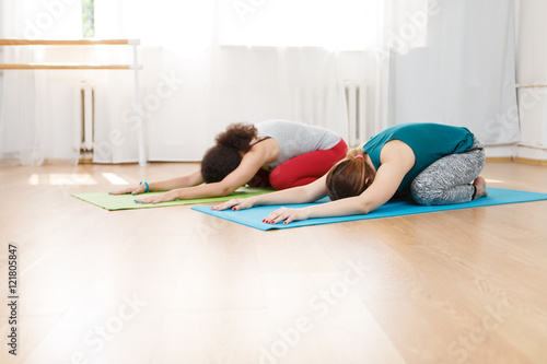 Two young women in sportswear doing exercise of yoga